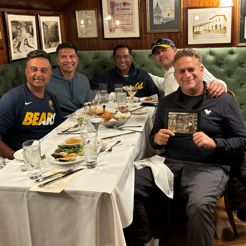 Four friends at a restaurant table, one holding up a sketch of the evening